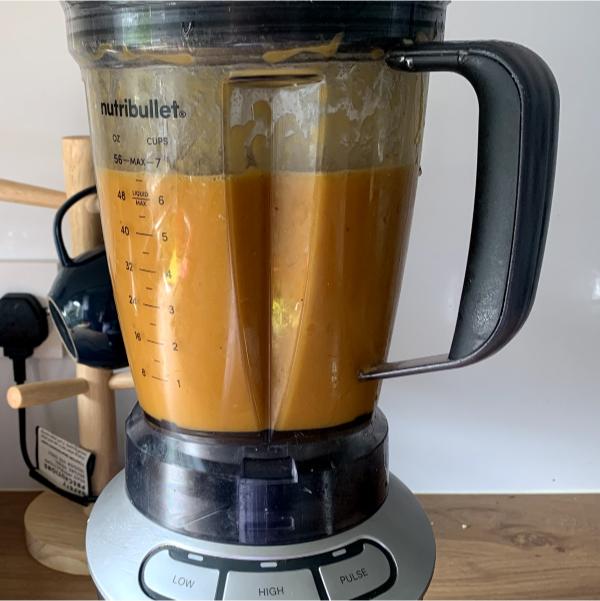 a blender filled with blended carrot and sweet potato soup