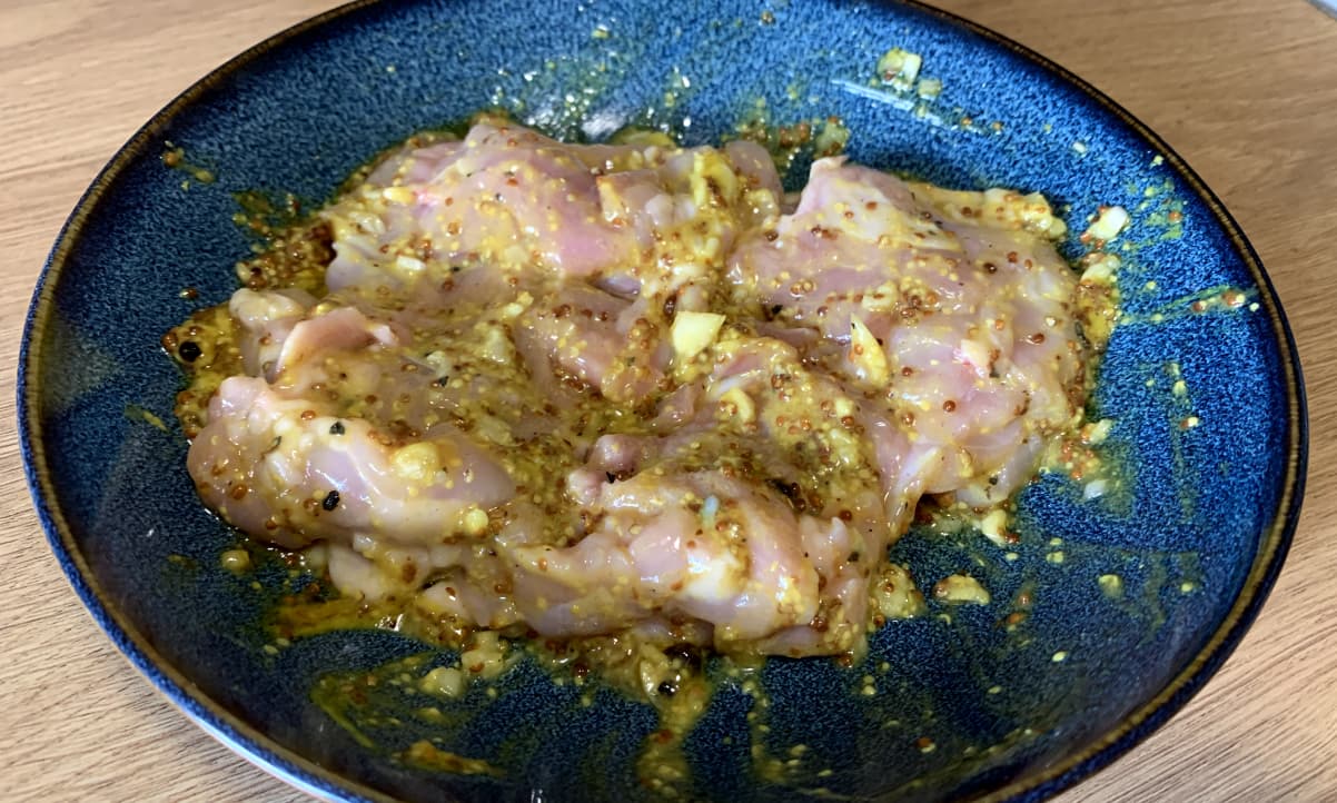 raw chicken marinading in a yellow mustard sauce