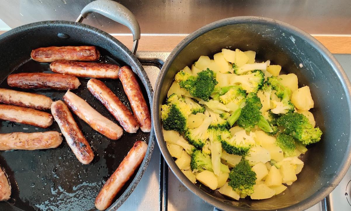 a pan full of frying sausages, and a pot full of cubed boiled potatoes and broccoli next to it