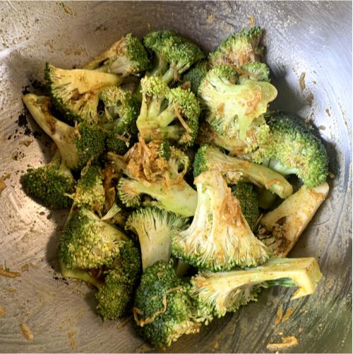 broccoli florets seasoned with spices in a metal bowl