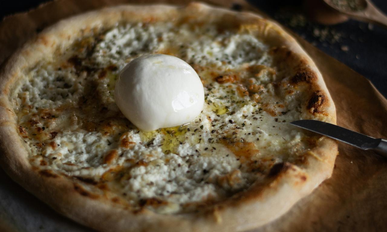 a pizza with a large ball of burrata placed on top