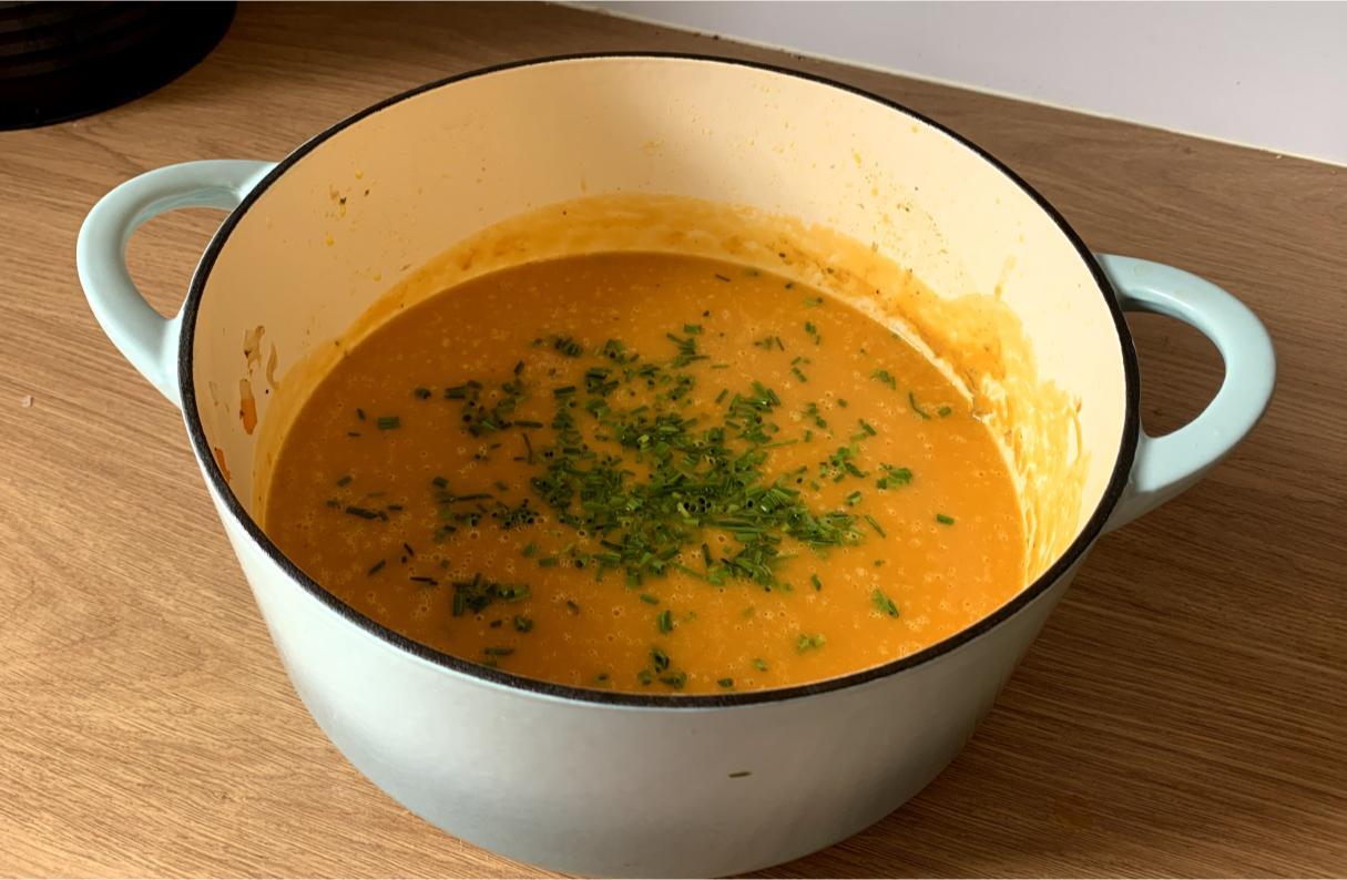 a pot of sweet potato and carrot soup, garnished with chives