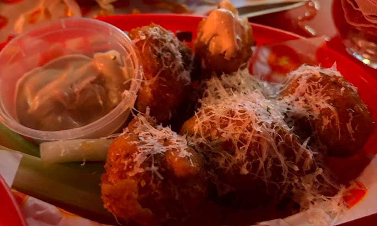 cauliflower bites dusted with hard cheese with a creamy dip and sticks of fresh celery