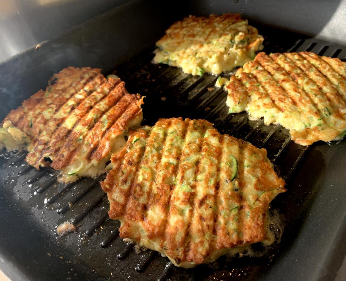 golden cheddar and courgette patties in a griddle pan