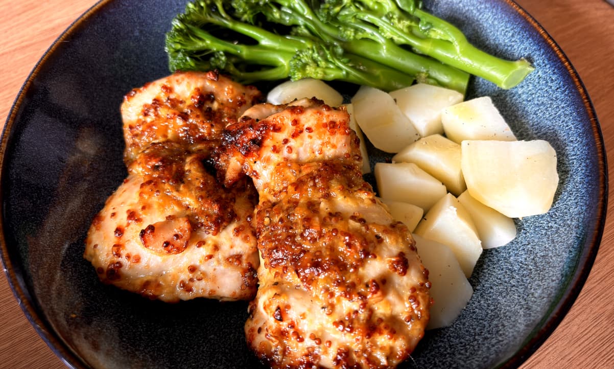 roasted chicken thighs with wholegrain mustard sauce, servec with boiled potatoes and broccoli in a blue bowl