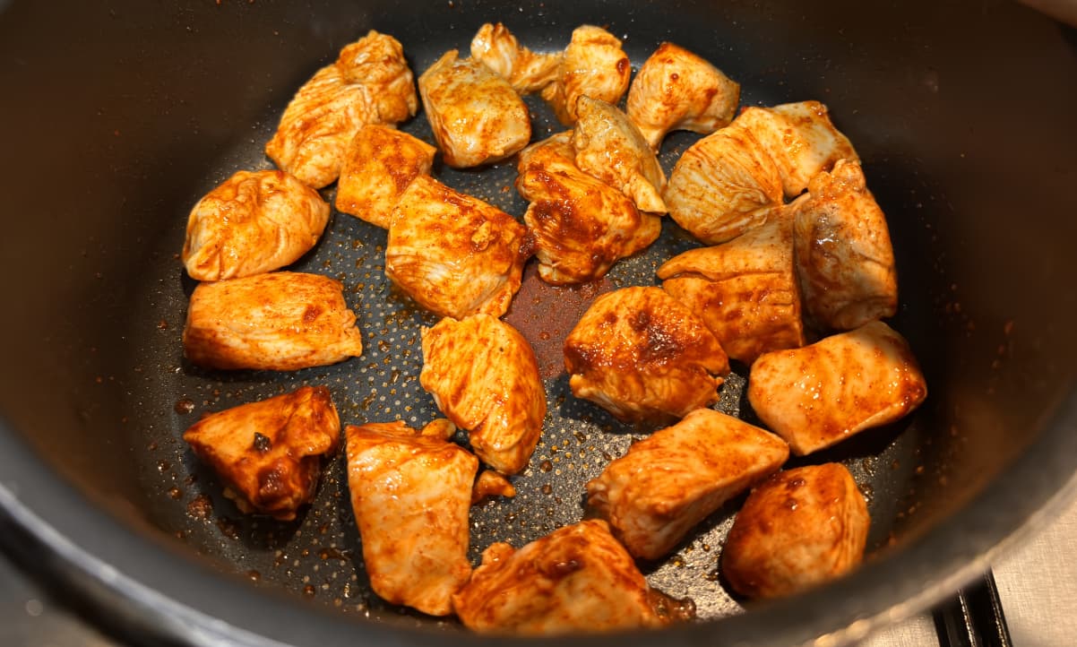 chicken and paprika frying in a black pan