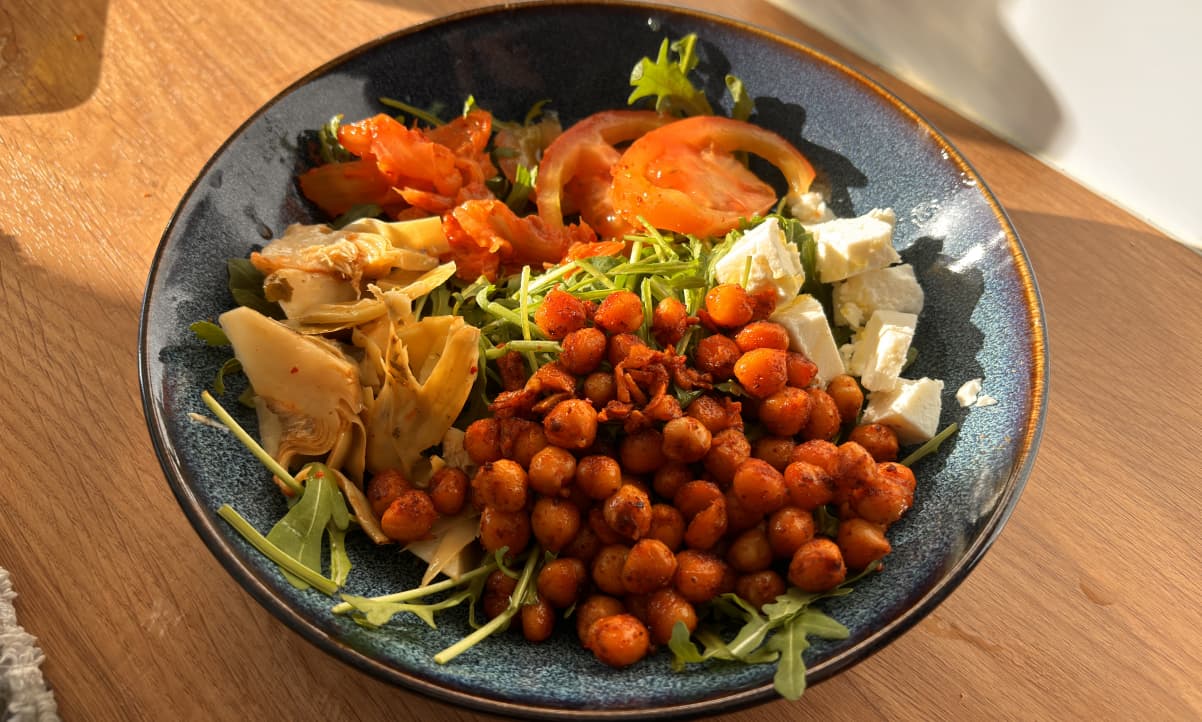 smoked paprika pan fried chickpea salad in a blue bowl with rocket, feta and artichokes