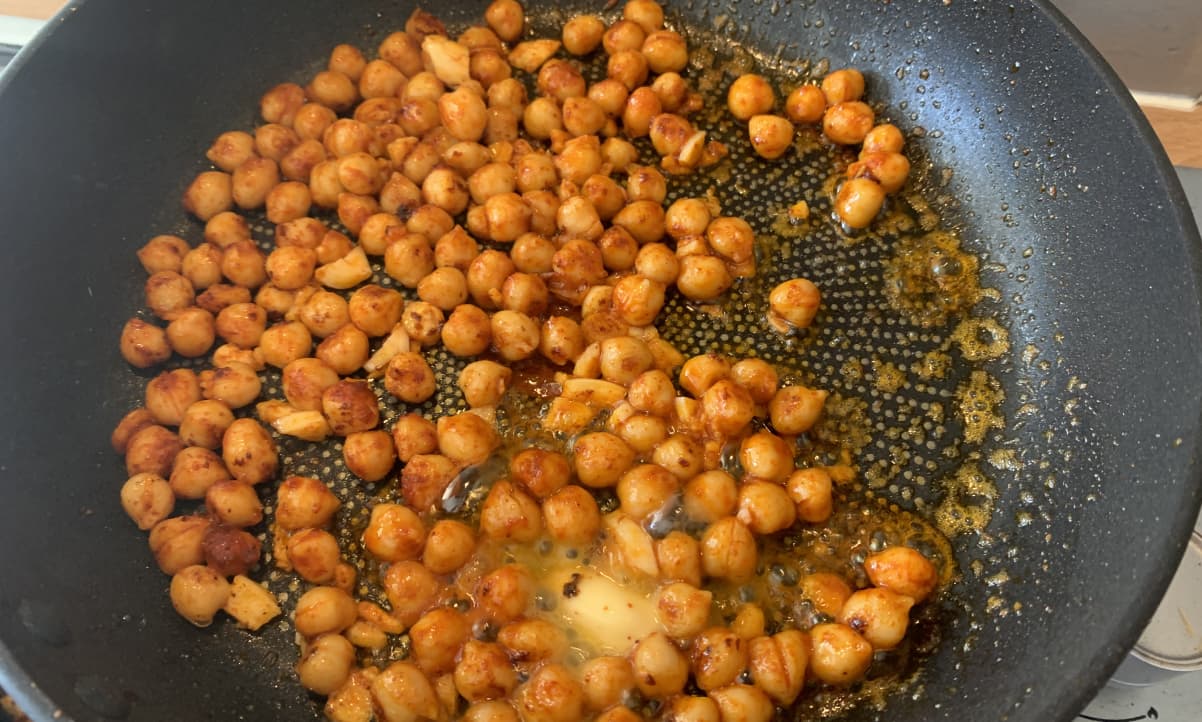 chickpeas and paprika frying in butter in a black pan