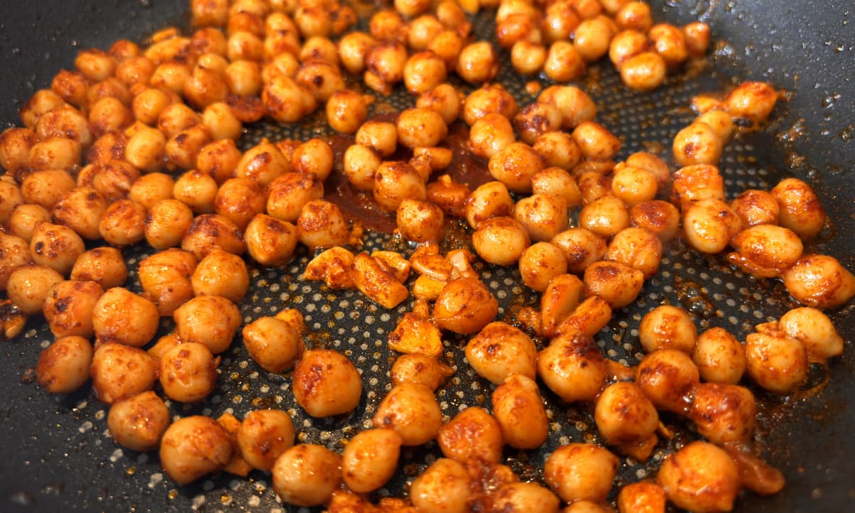 pan fried chickpeas covered in red spice in a non-stick pan