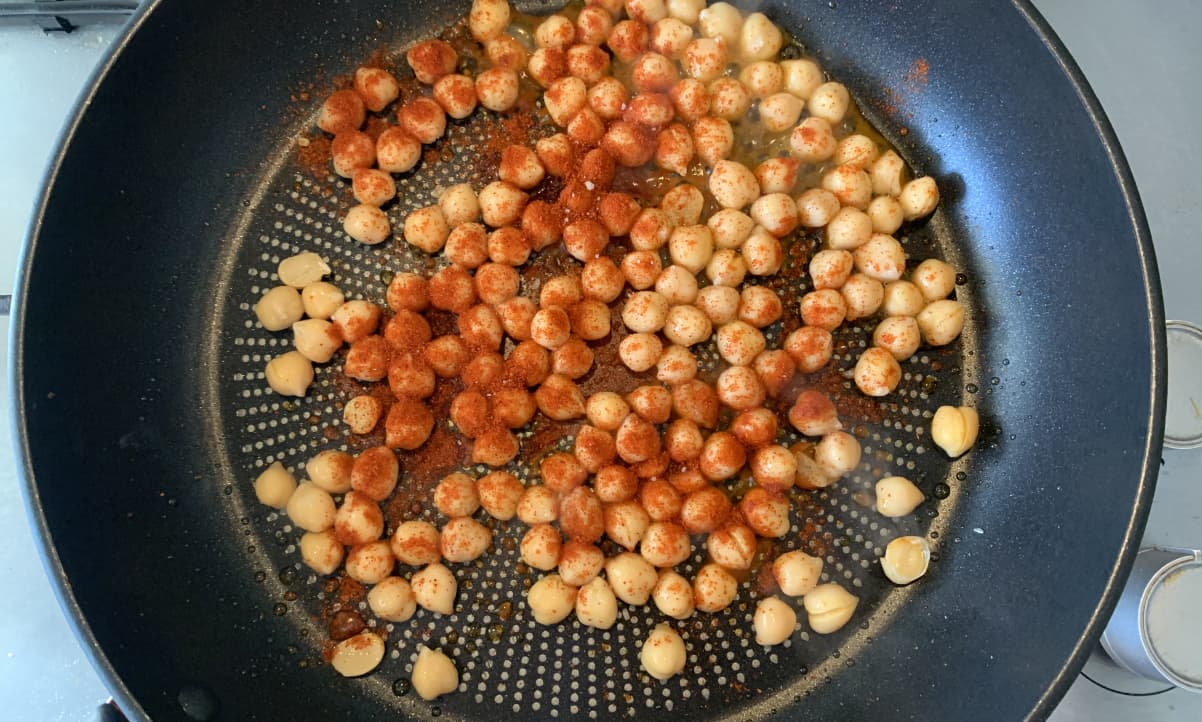 chickpeas and red powdered spice frying in a pan