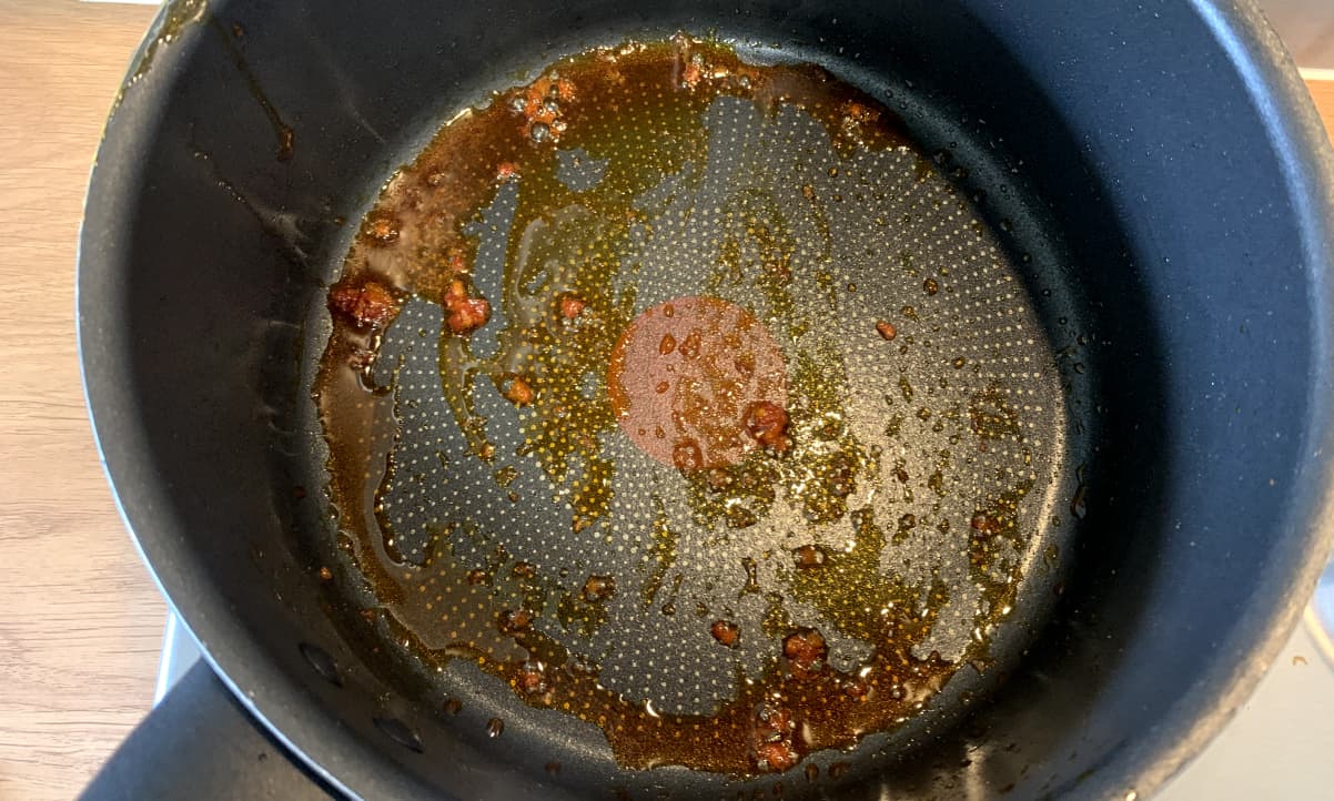 red oil in the bottom of a black cooking pot