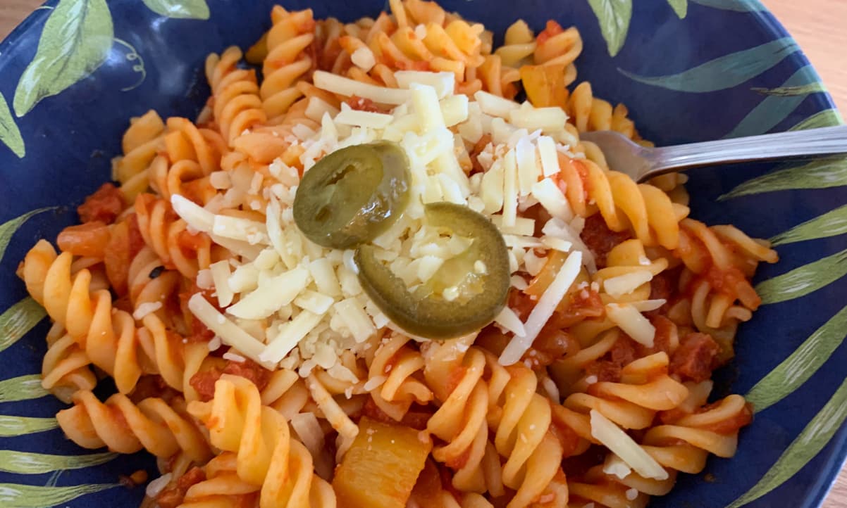 fusilli in a red sauce, garnished with grated cheese and two green jalapeno slices