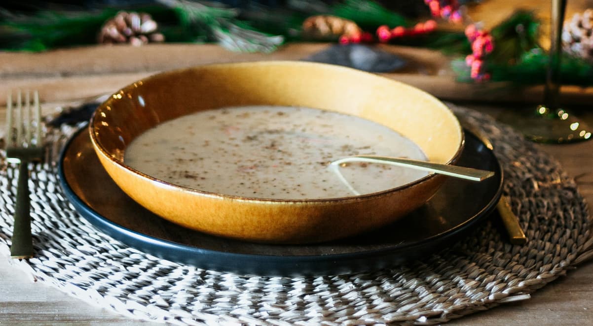 a golden soup bowl on a christmas dinner table, with cream coloured soup inside