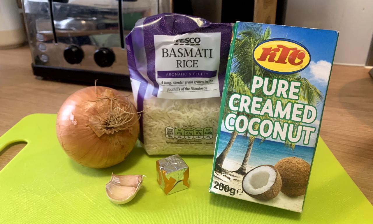 an assortment of ingredients on a green chopping board including a small cardboard box of creamed coconut