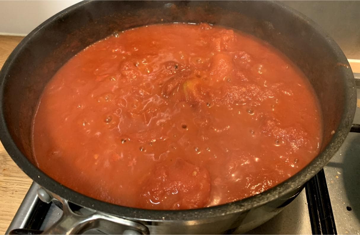 peeled plum tomatoes gently bubbling in a pan