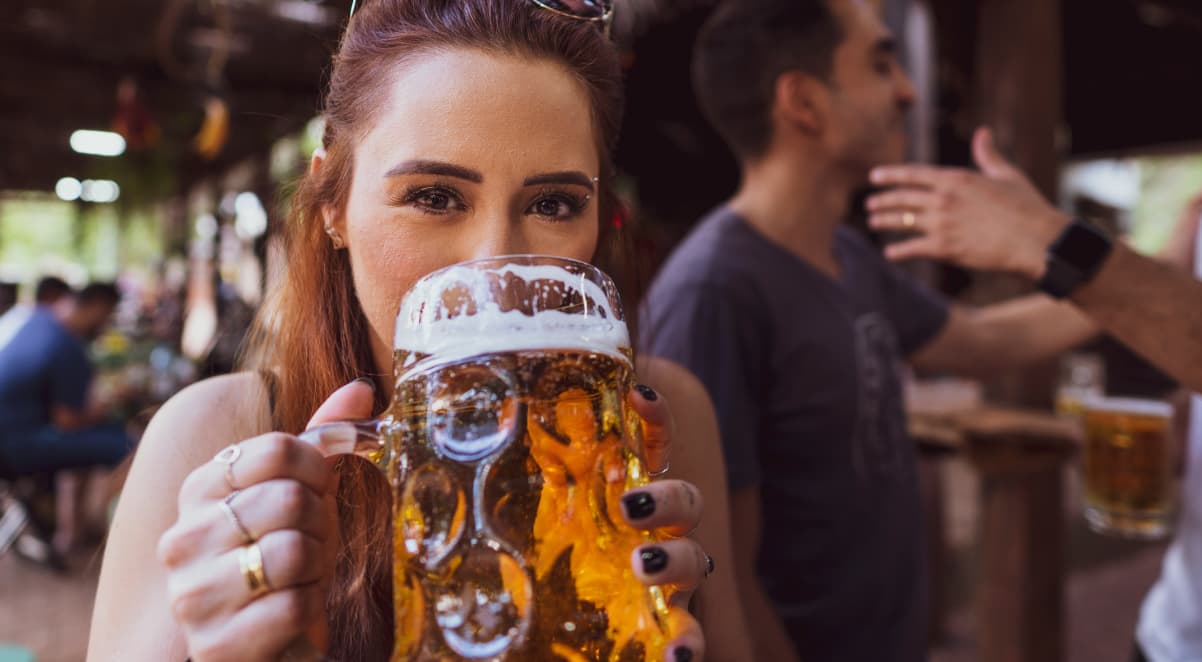 a young, red haired woman drinking beer from a large jug