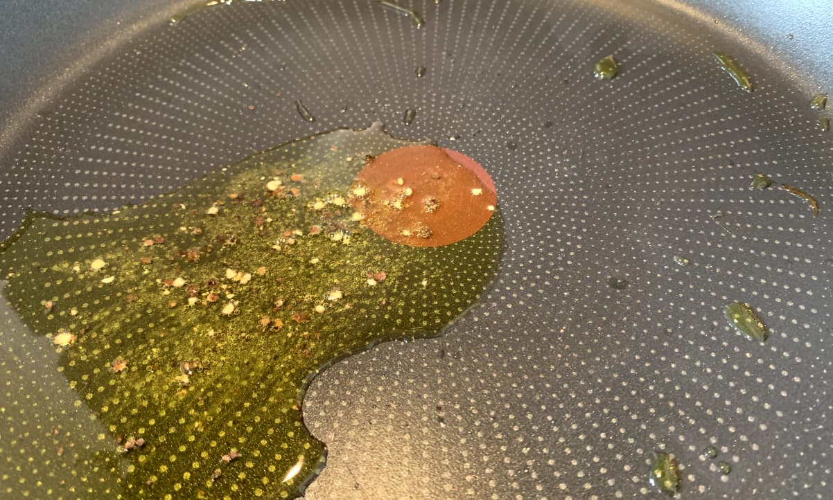 black pepper frying in oil in a wide non-stick pan