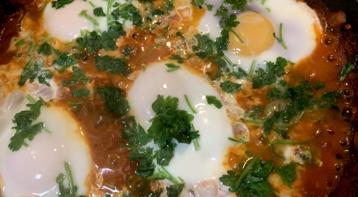 eggs cooking in red shakshouka sauce