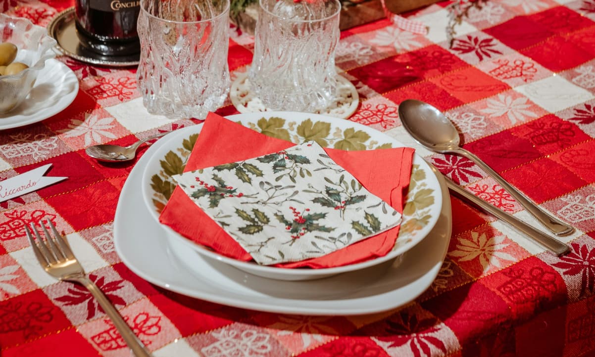 a table adorned with a Sred and white tartan tablecloth and christmas themed napkins on the plate for Scottish Christmas dinner