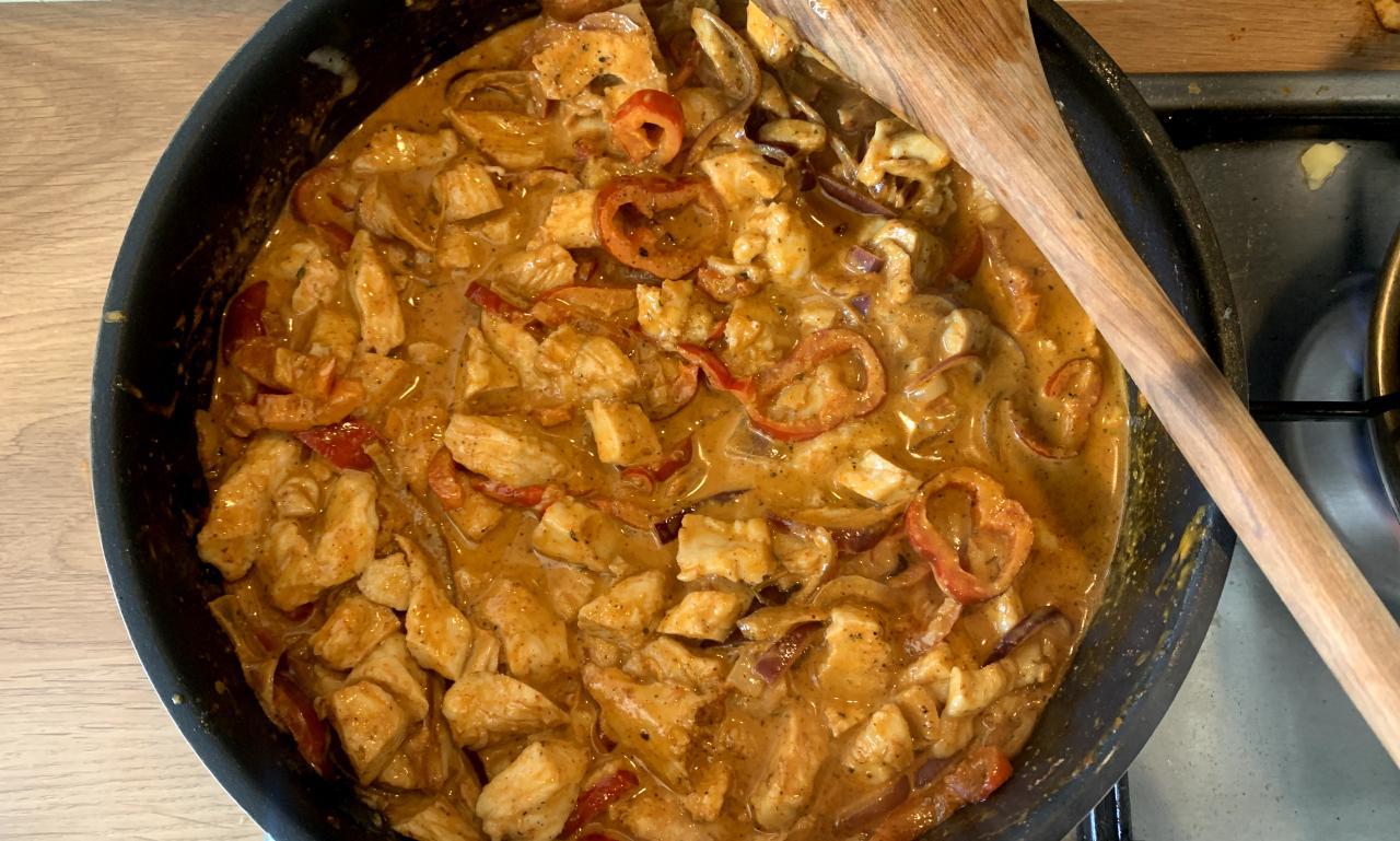 fajita pasta sauce made with frozen cooked chicken, with sliced red pepper and cream, cooking in a pan