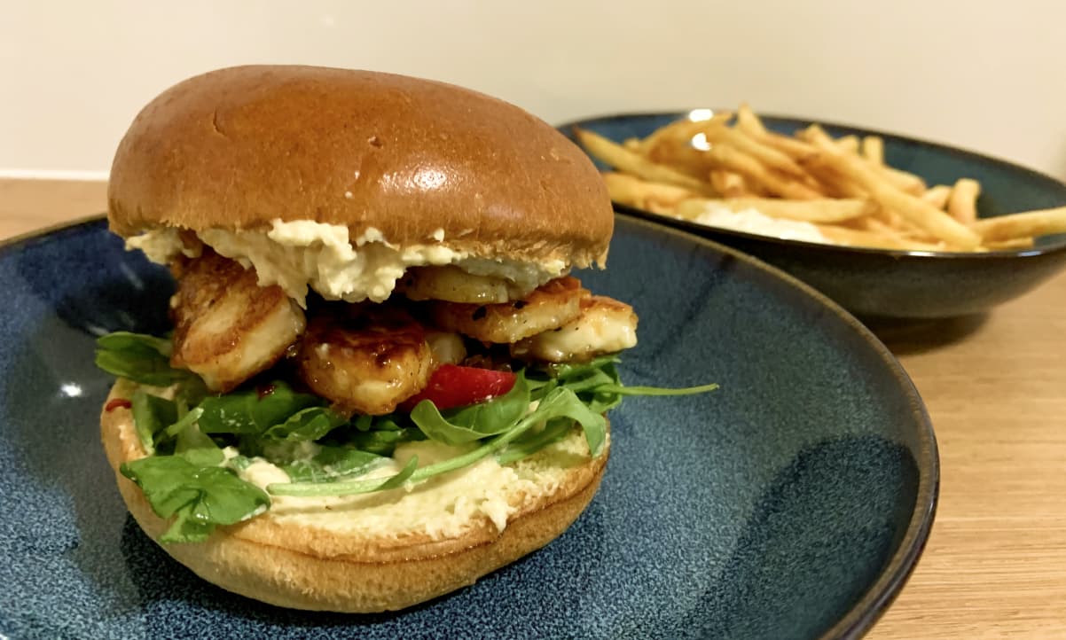 halloumi burger with hummus, rocket salad and chips in the background