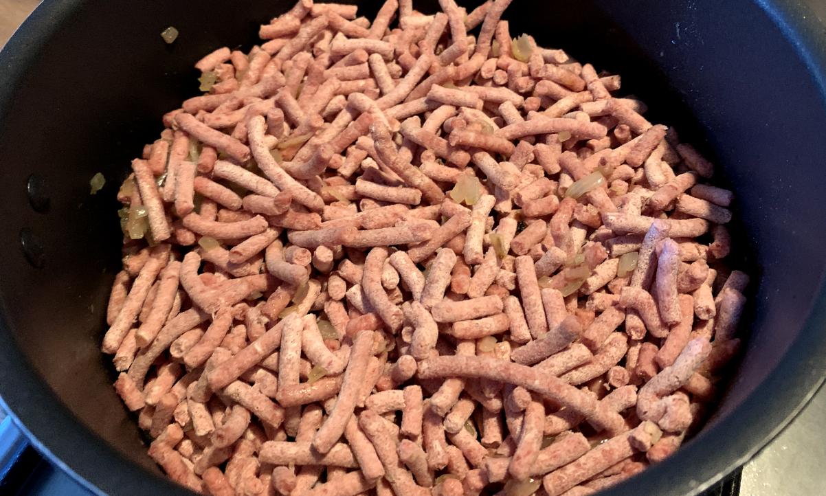 frozen mince heating in a black cooking pot