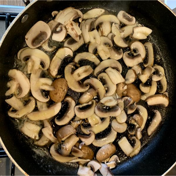 sliced mushrooms frying in a pan