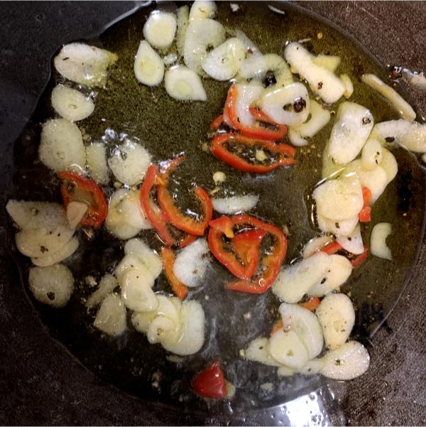 thinly sliced chilli and garlic frying in a pan