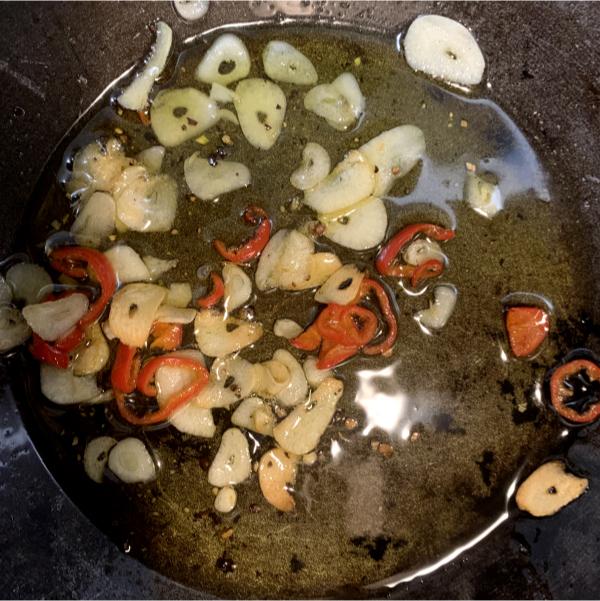 thinly sliced garlic and chilli frying in a pan