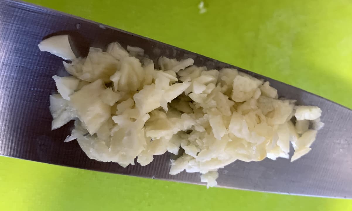 minced garlic on the flat edge of a knife