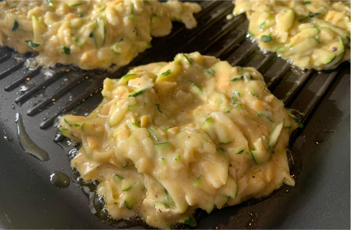 cheddar and courgette patties cooking in a griddle pan