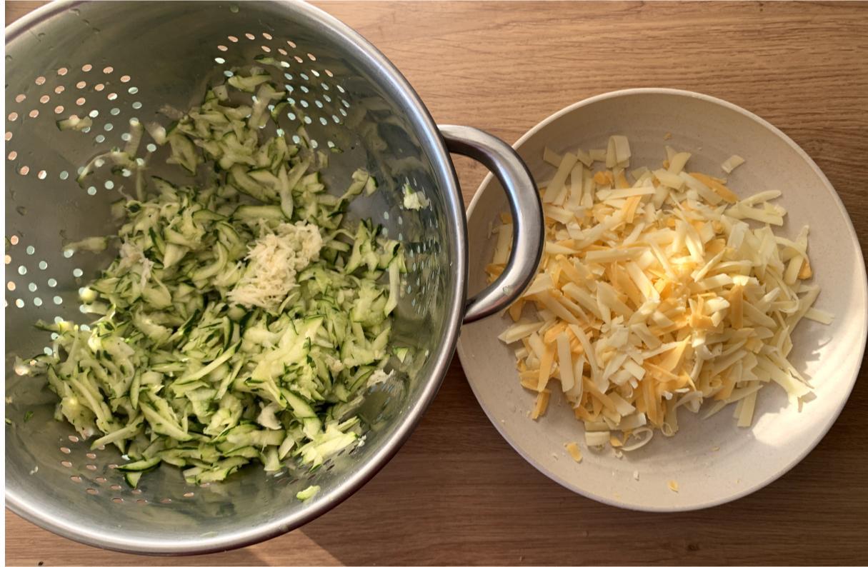 grated cheddar on a plate and a colander with grated courgette inside