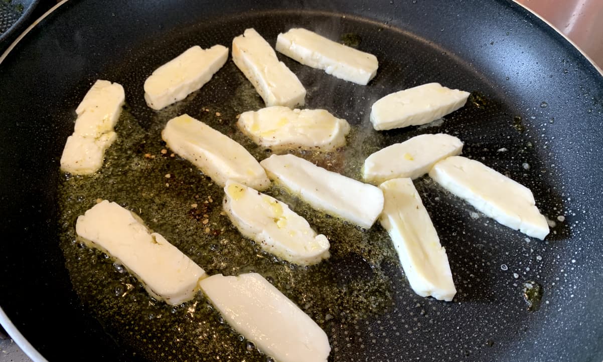 slices of halloumi frying in a pan