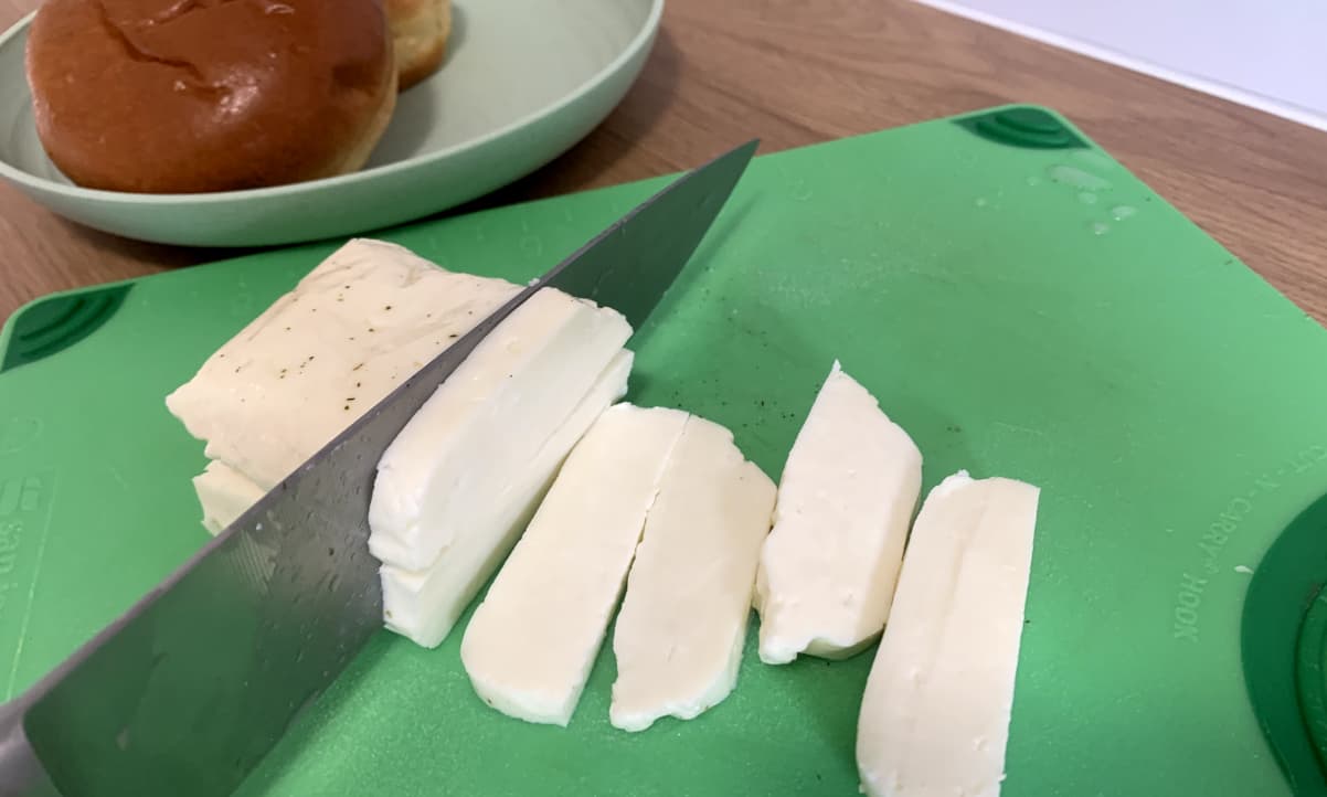 a large knife cutting a block of fresh halloumi into slices