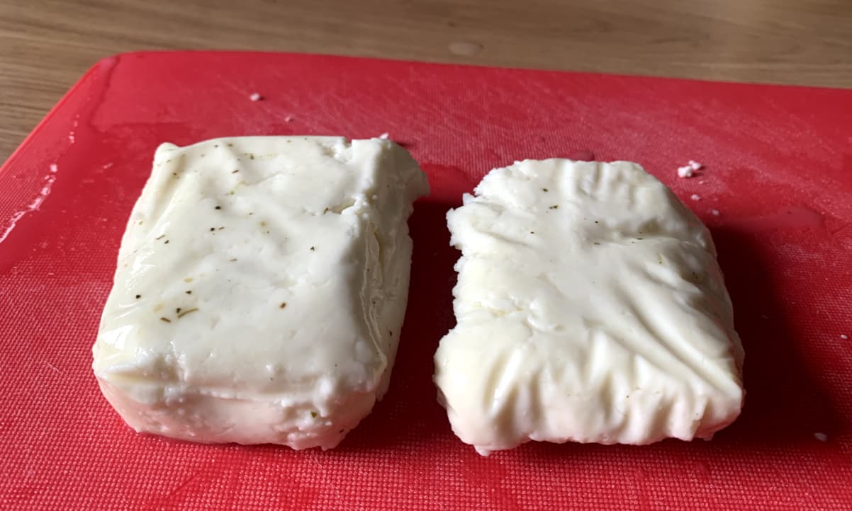 a block of halloumi, cut in half, on a red chopping board