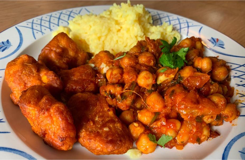 chickpea curry, rice and chicken pakora arranged together on an elegant blue and white plate.