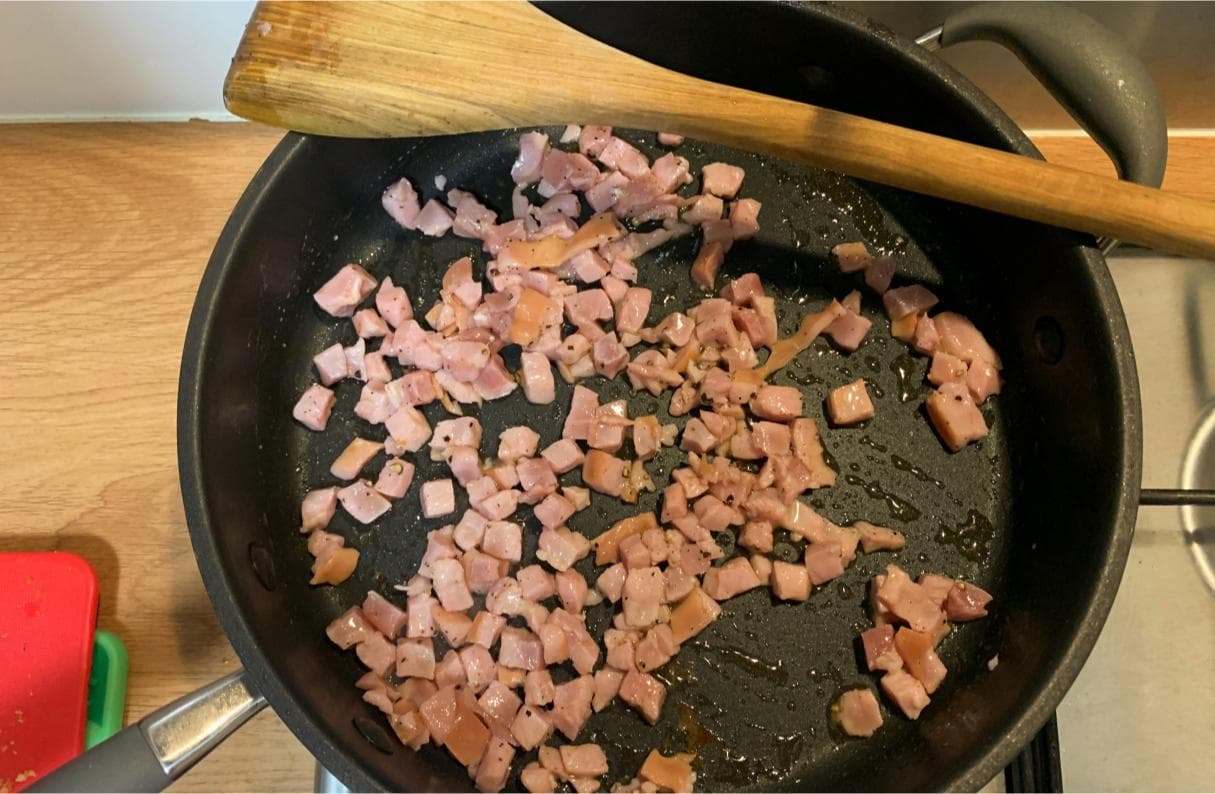 bacon lardons frying in a pan