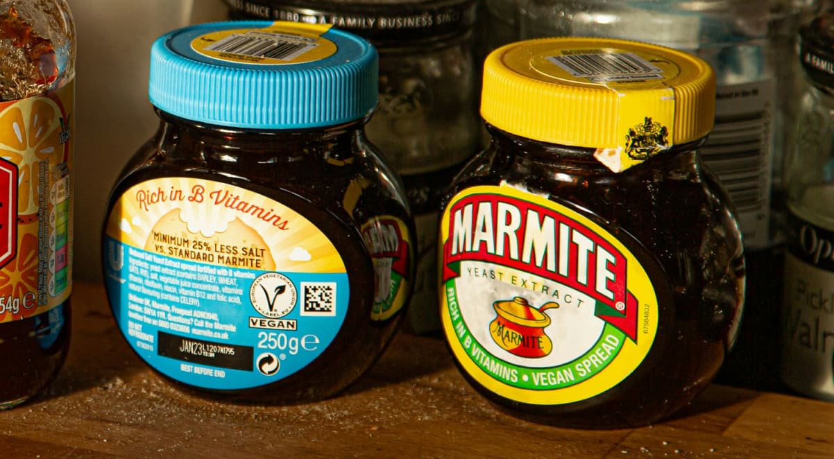 two black jars of marmite side by side, with a yellow lid and one with a blue lid