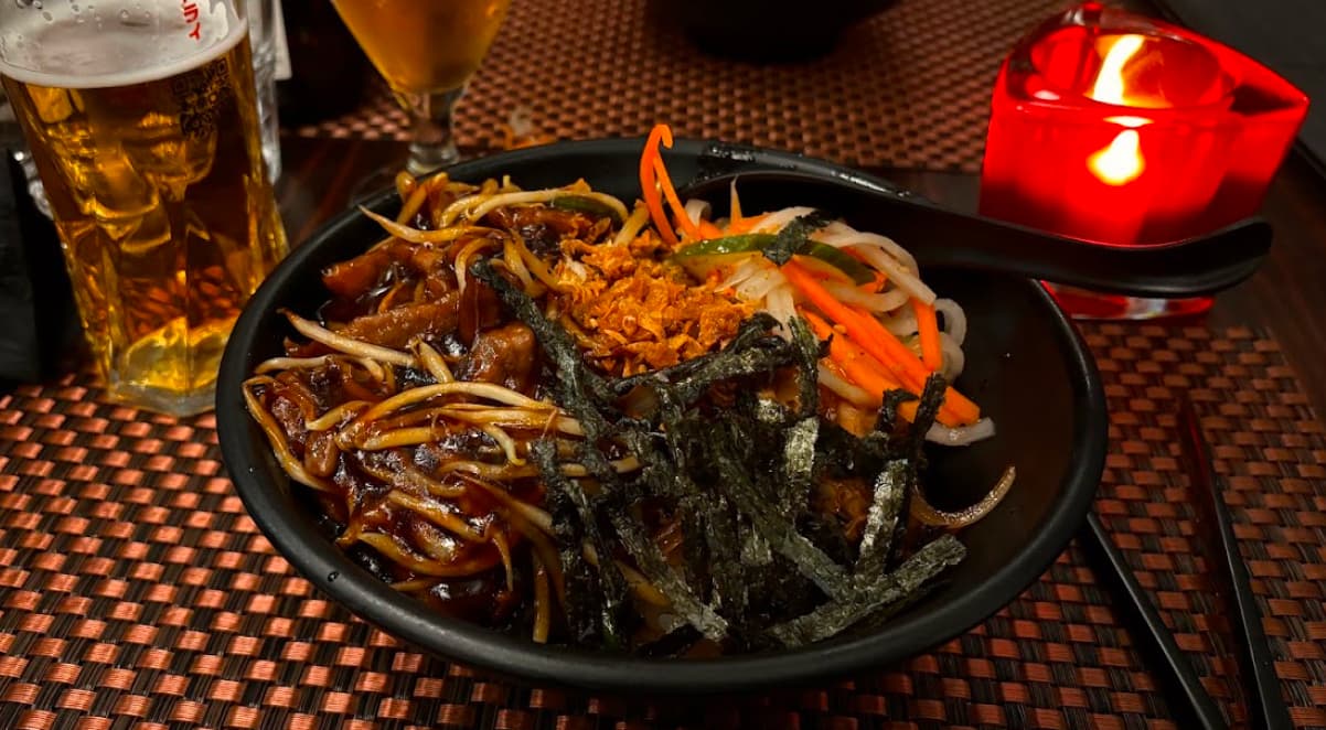 a bowl containing a selection of meat, bean sprouts, seaweed and fresh vegetables