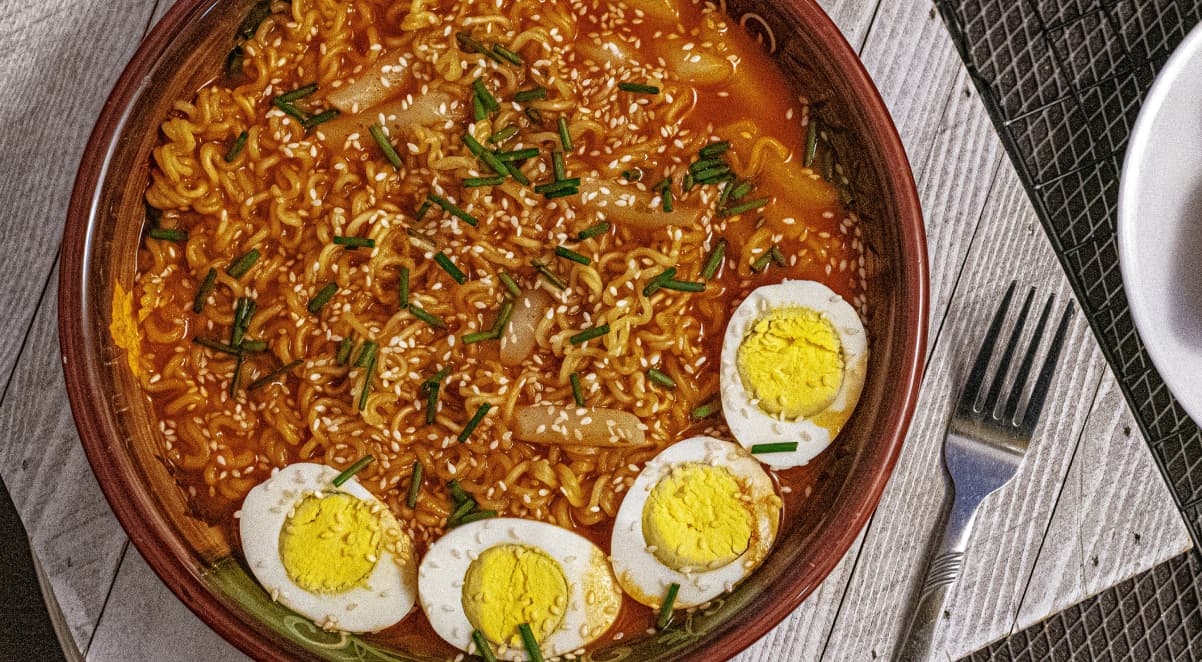 a large bowl of ramen in a red broth, garnished with several boiled eggs