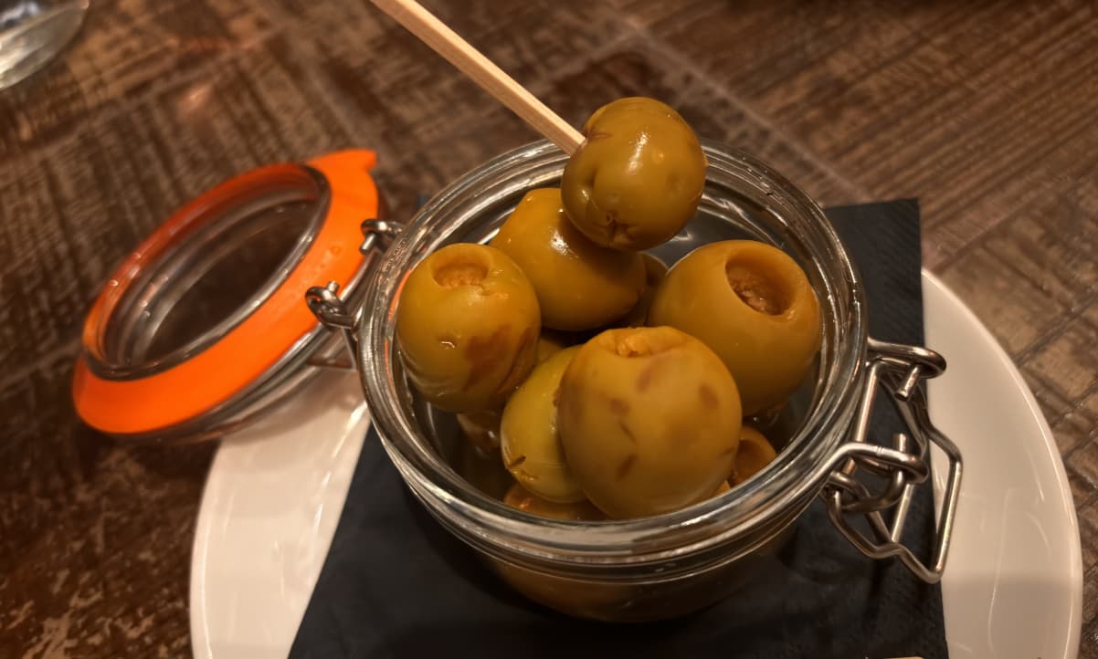 a small glass ramekin full of large green olives