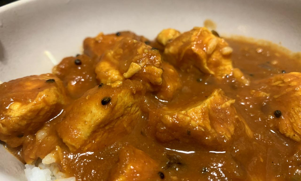 chicken curry with onion seeds served on white rice in a bowl