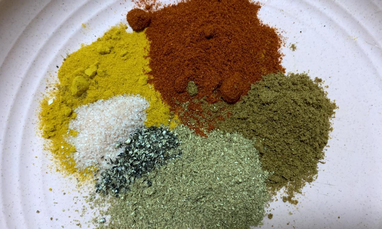 a selection of powdered spices of different colours on a plate