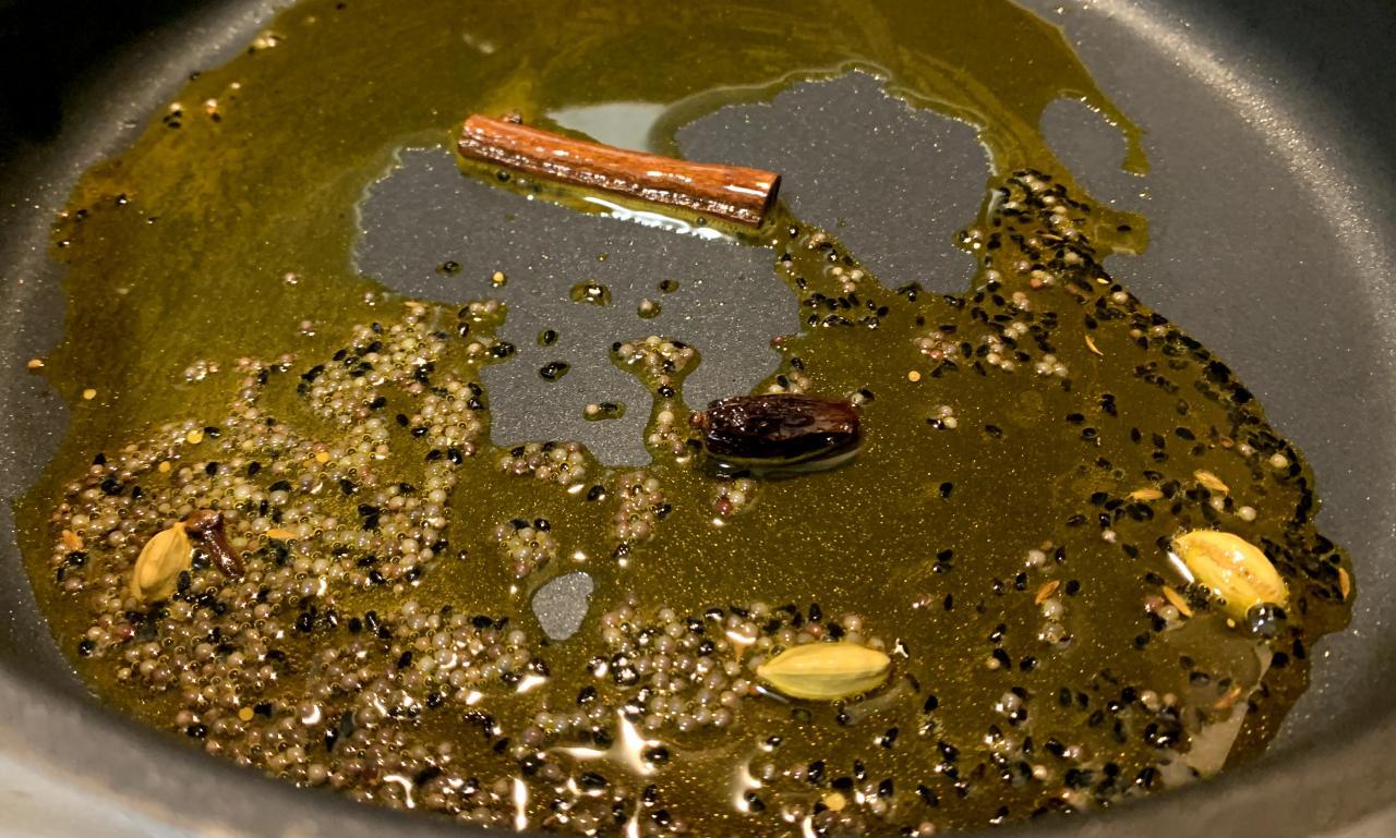 whole spices (including cinnamon, cardamom and onion seeds) frying in a pan