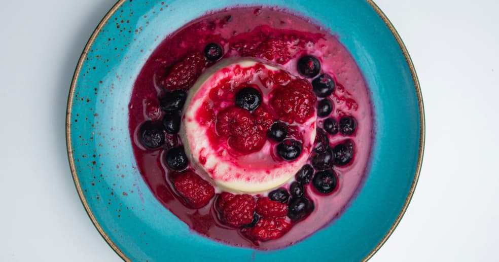 a panna cotta, garnished with raspberries and blueberries, photographed from above