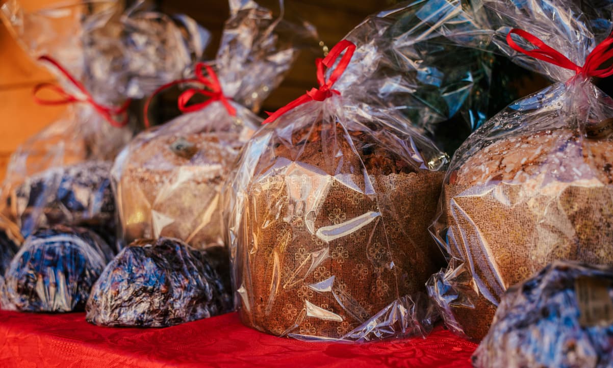 large cakes, wrapped in see through plastic tied with red ribbons, on a stall