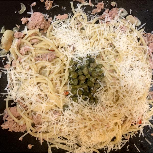 spaghetti with tuna, capers and chilli cooking in a pan with some grated parmigiano reggiano