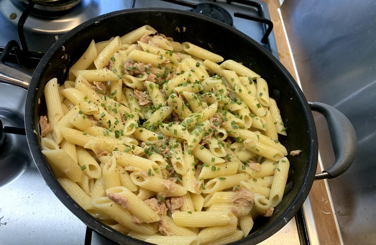 aglio e olio with tuna, garnished with chives, presented in a pan