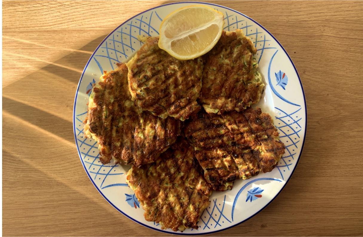 cheddar and courgette patties on a plate, garnished with a lemon wedge