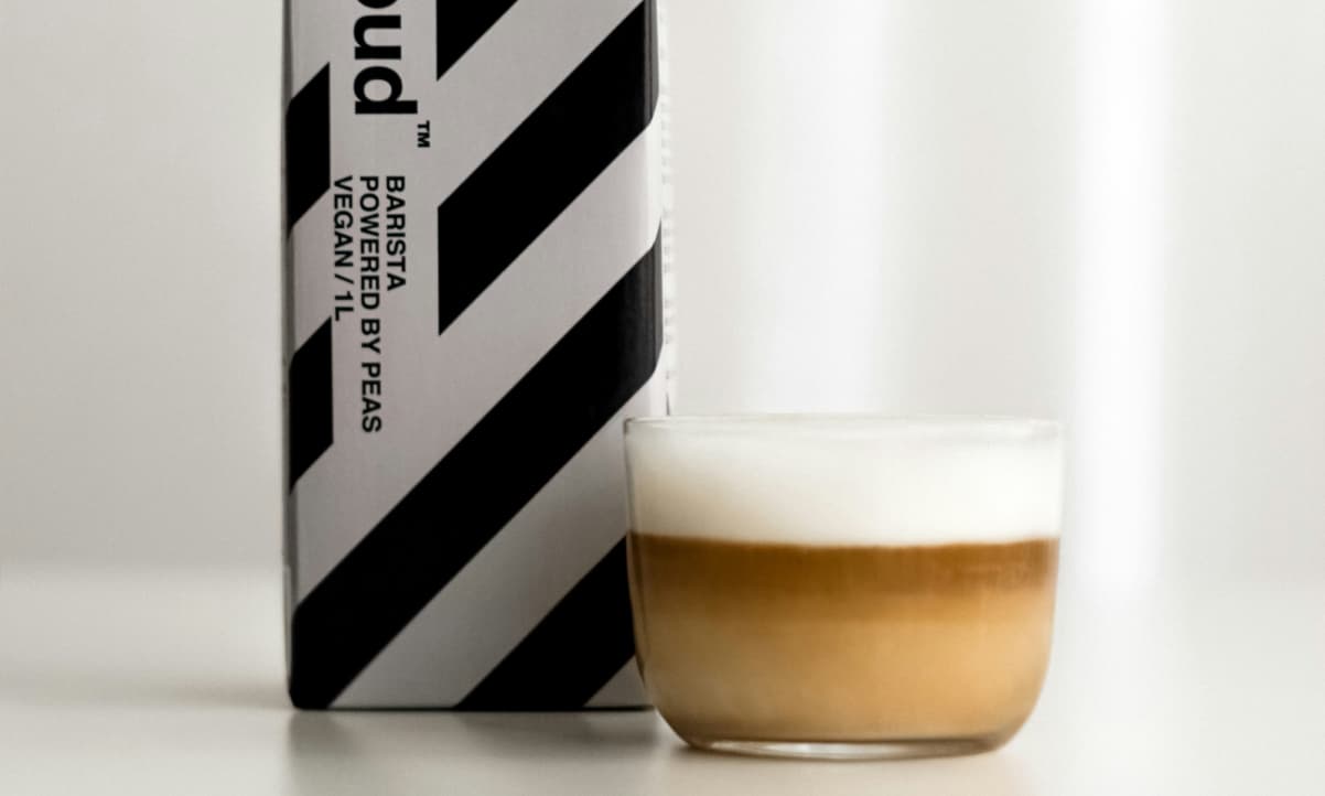 a black and white milk carton next to a cappiccino in a transparent glass